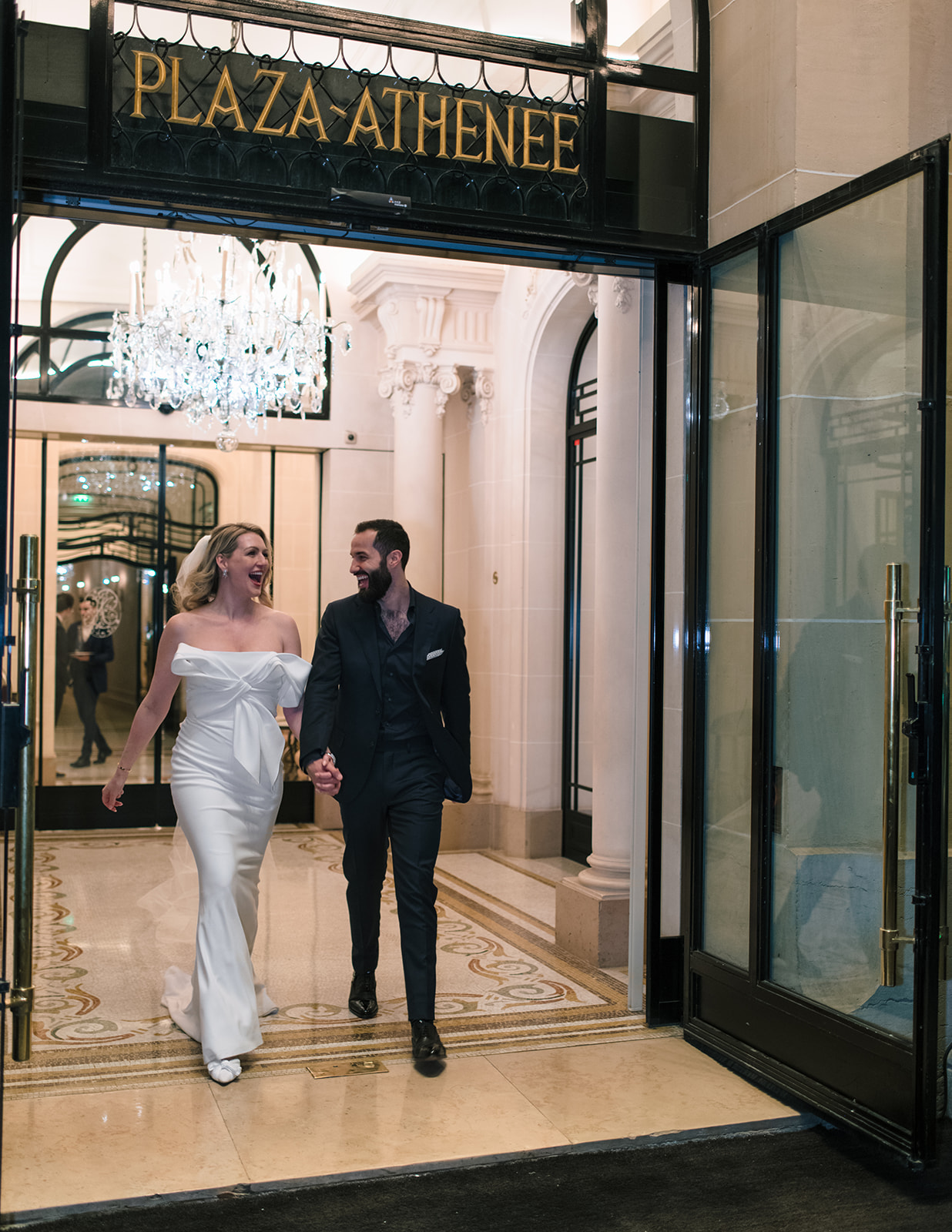 Newlyweds walking through the entrance of Hôtel Plaza Athénée Paris